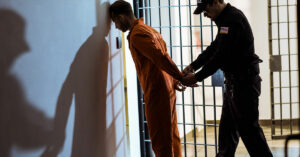 Side view of prison officer wearing handcuffs on prisoner