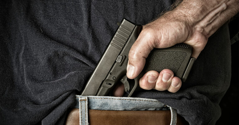 Man pulling a gun from behind his wasteband