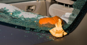 Landscape orientation of a car's rear window smashed out by a pumpkin.